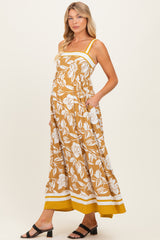 woman wearing a mustard yellow floral print maternity maxi dress with pockets and a baby bump visible