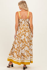 woman wearing a brown floral maternity maxi dress with elastic smocking and yellow accents, showing her back