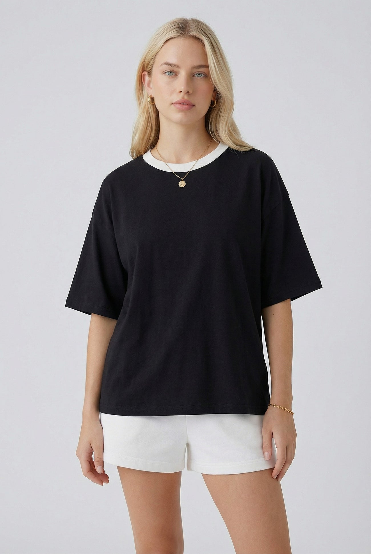 woman wearing a black oversized t-shirt with a white collar paired with white shorts