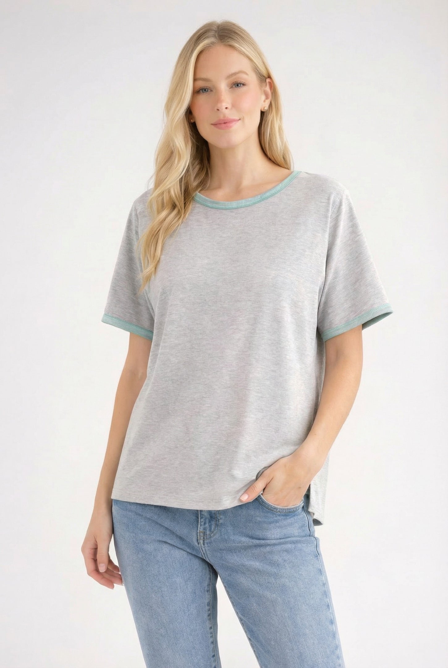 woman wearing a gray short sleeve t-shirt with teal trim and blue high-waisted jeans