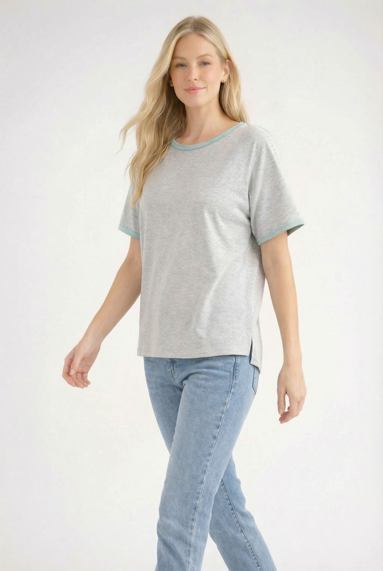 woman wearing a gray short sleeve t-shirt with teal trim and side slits, paired with light blue jeans