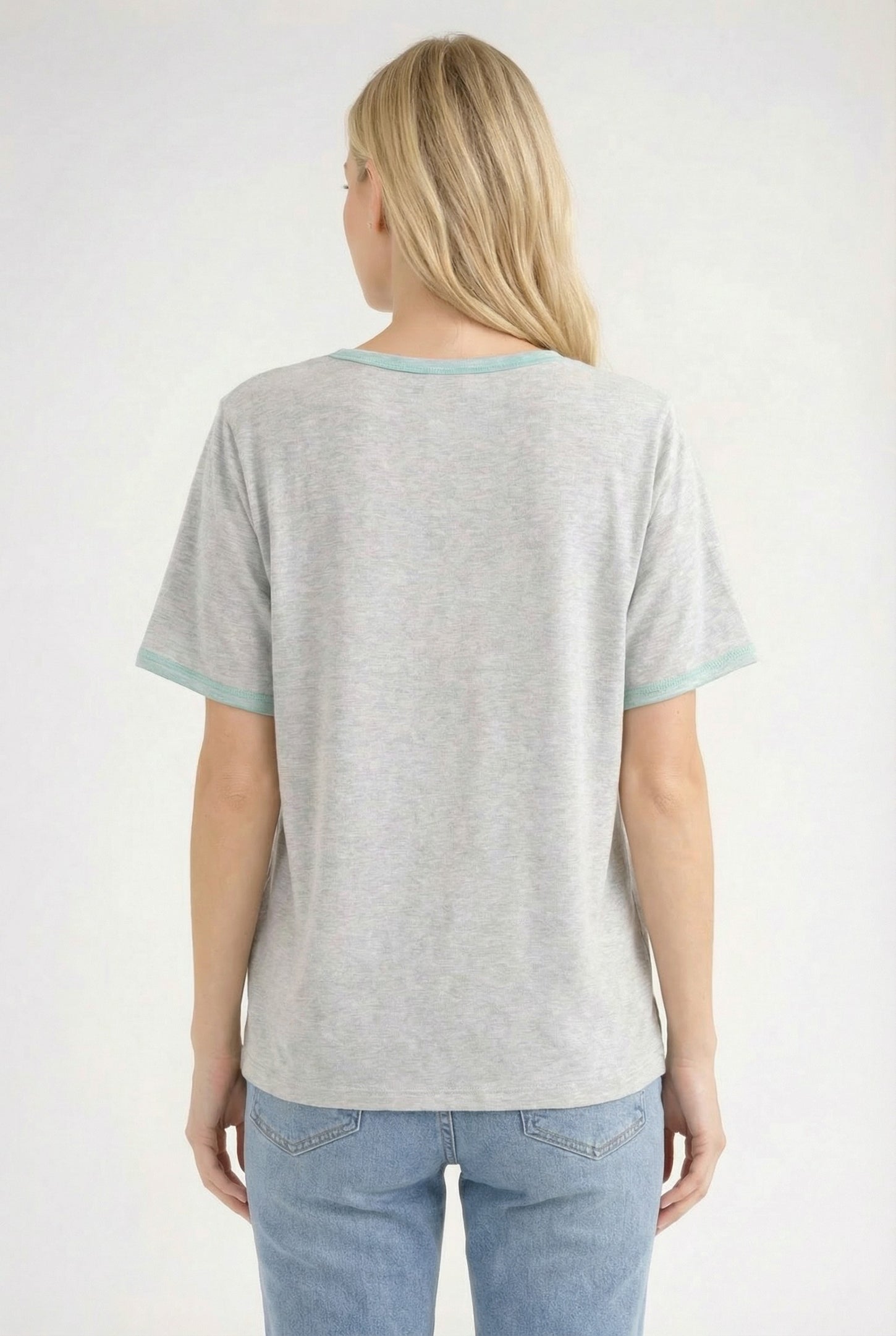 woman wearing a gray short sleeve t-shirt with teal trim and light blue jeans, viewed from the back