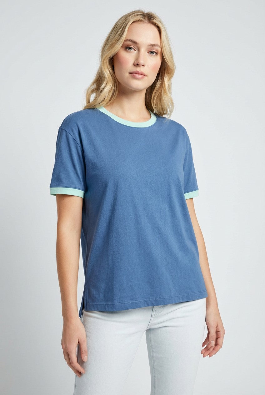 woman wearing a blue short sleeve t-shirt with mint green trim and white jeans