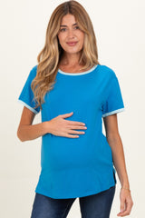 woman wearing a teal maternity top with short sleeves and contrasting trim, holding her baby bump