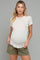 woman wearing a beige short sleeve maternity top and olive green shorts, showing her baby bump