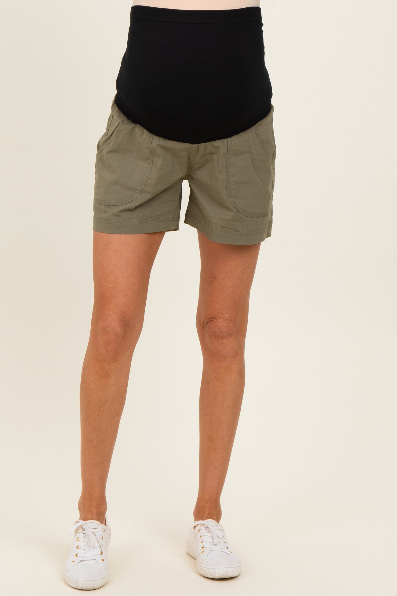 woman wearing olive green maternity shorts with a black over-the-bump waistband and pockets