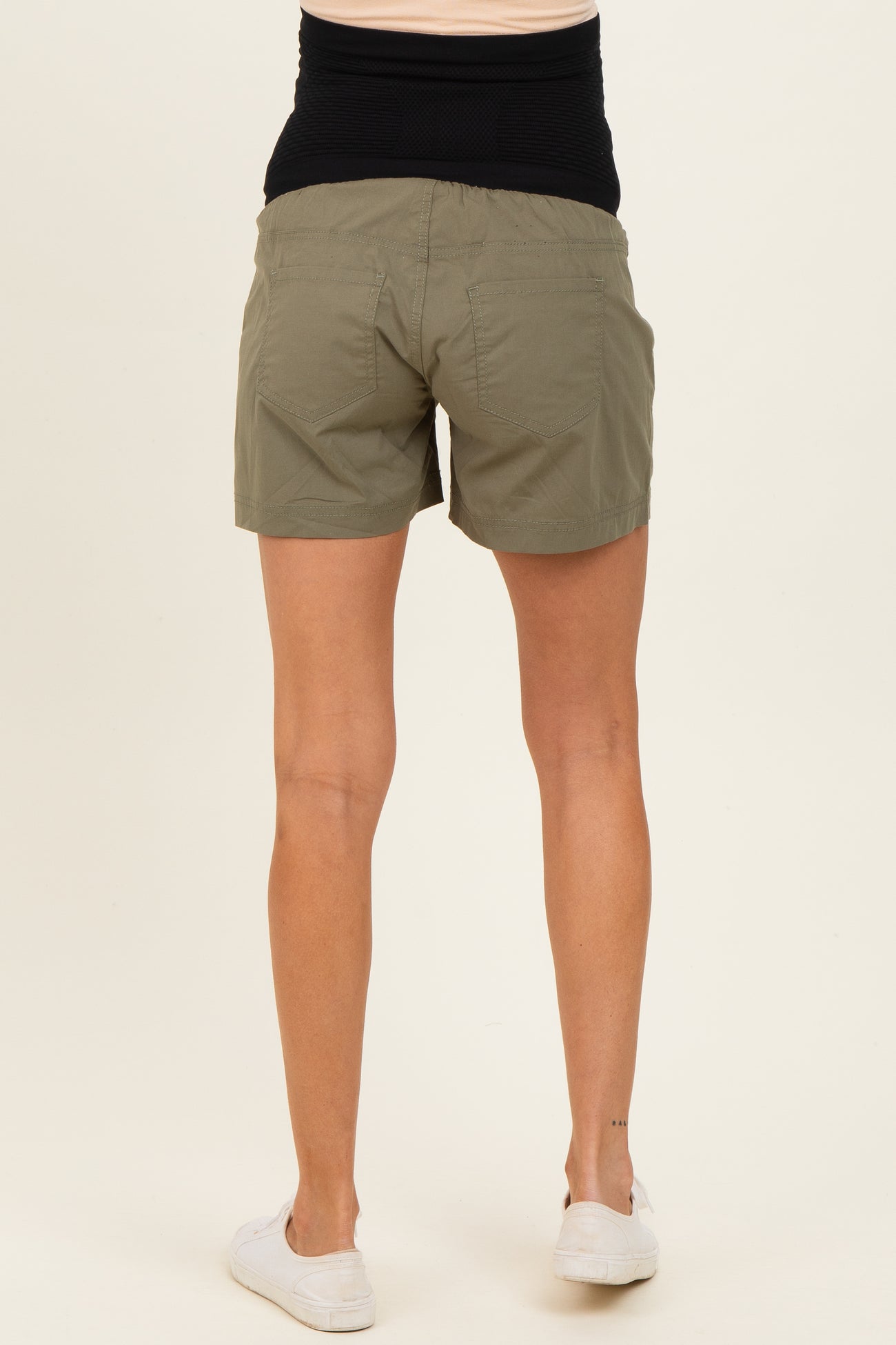 woman wearing olive green maternity shorts with a black waistband, viewed from the back
