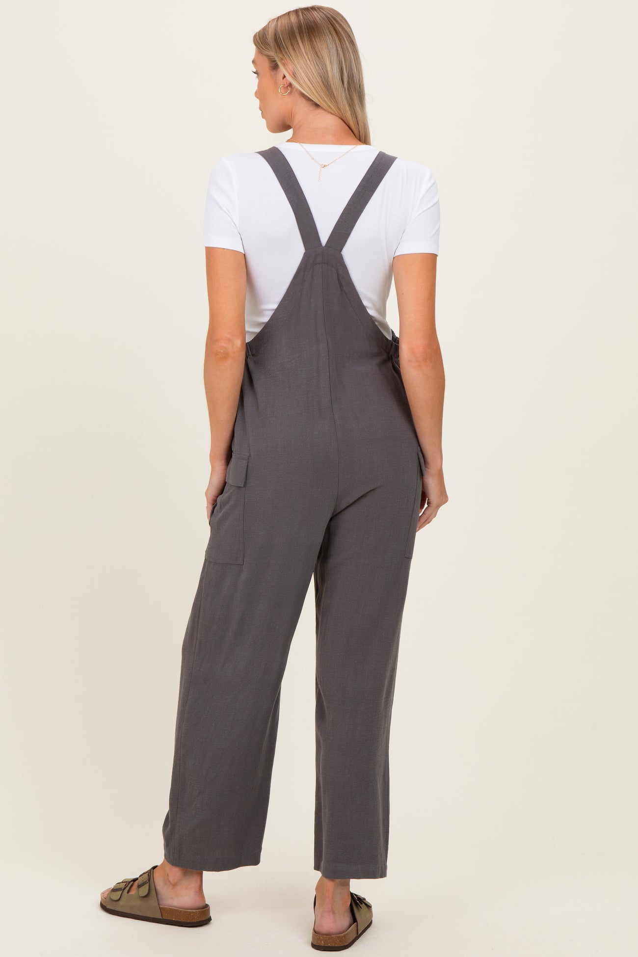 woman wearing gray maternity overalls with a white t-shirt underneath, showing a comfortable and stylish fit