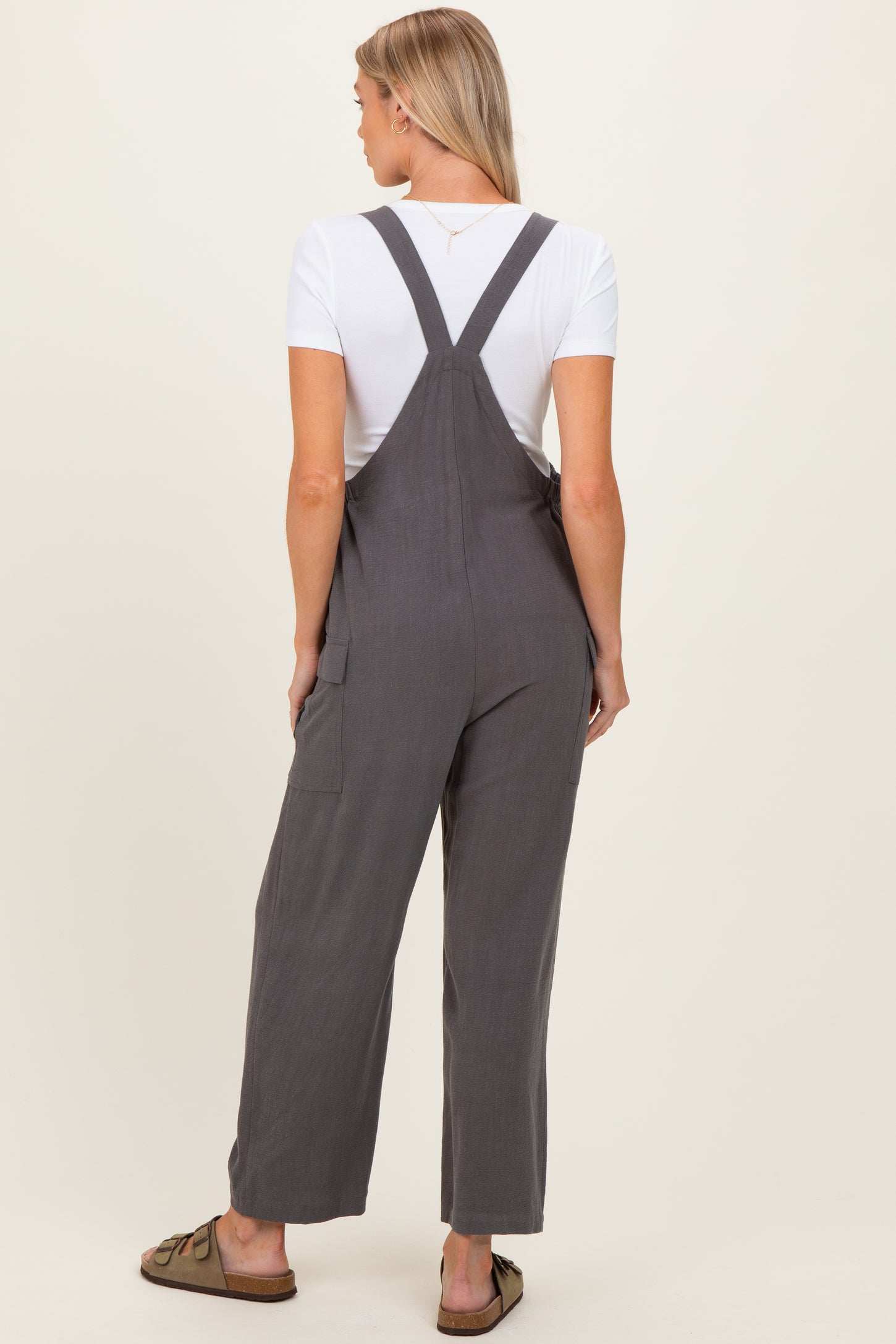 woman wearing gray maternity overalls with a white t-shirt underneath, showing a comfortable and stylish fit