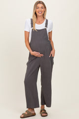 woman wearing a grey maternity overall with a white t-shirt underneath and holding her baby bump