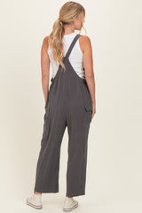 woman wearing a charcoal gray overall jumpsuit with back pockets and a white tank top underneath