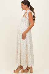 woman wearing a white floral maternity maxi dress with tie straps and a visible baby bump