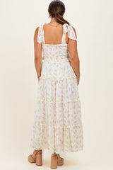 woman wearing a white floral tiered maxi dress with tie straps, showcasing her baby bump from the back