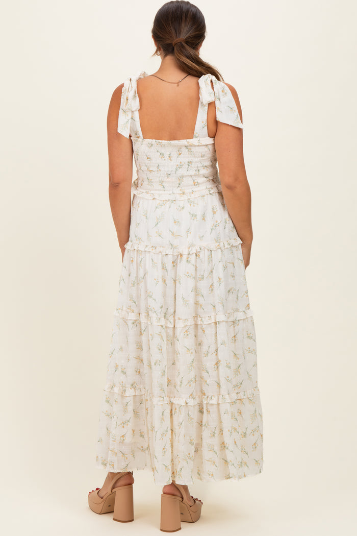 woman wearing a white floral tiered maxi dress with tie straps, showcasing her baby bump from the back