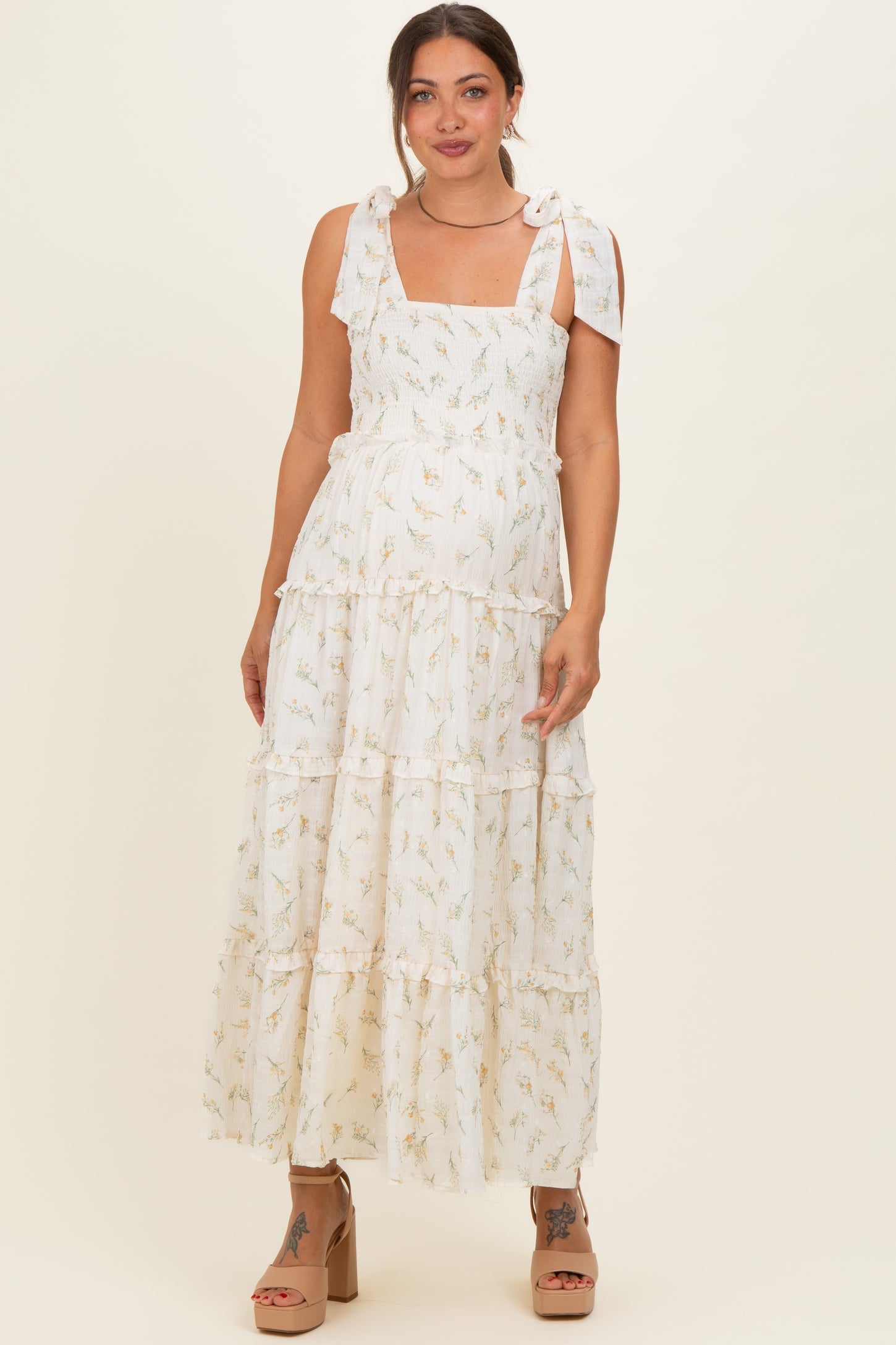 woman wearing a white floral maxi maternity dress with tie straps and a visible baby bump