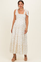woman wearing a white floral maxi maternity dress with tie straps and a visible baby bump
