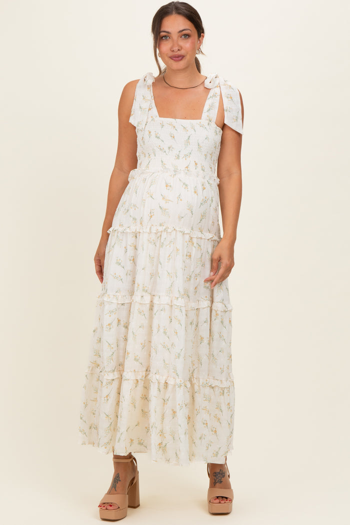 woman wearing a white floral maxi maternity dress with tie straps and a visible baby bump