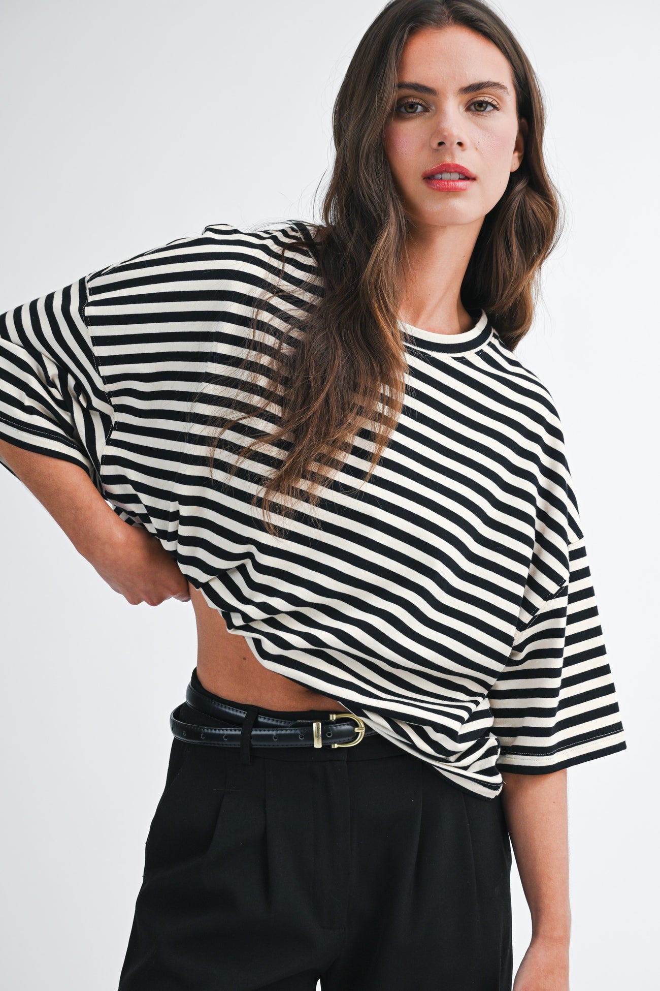 woman wearing a black and white striped oversized t-shirt with wide sleeves and high-waisted black trousers