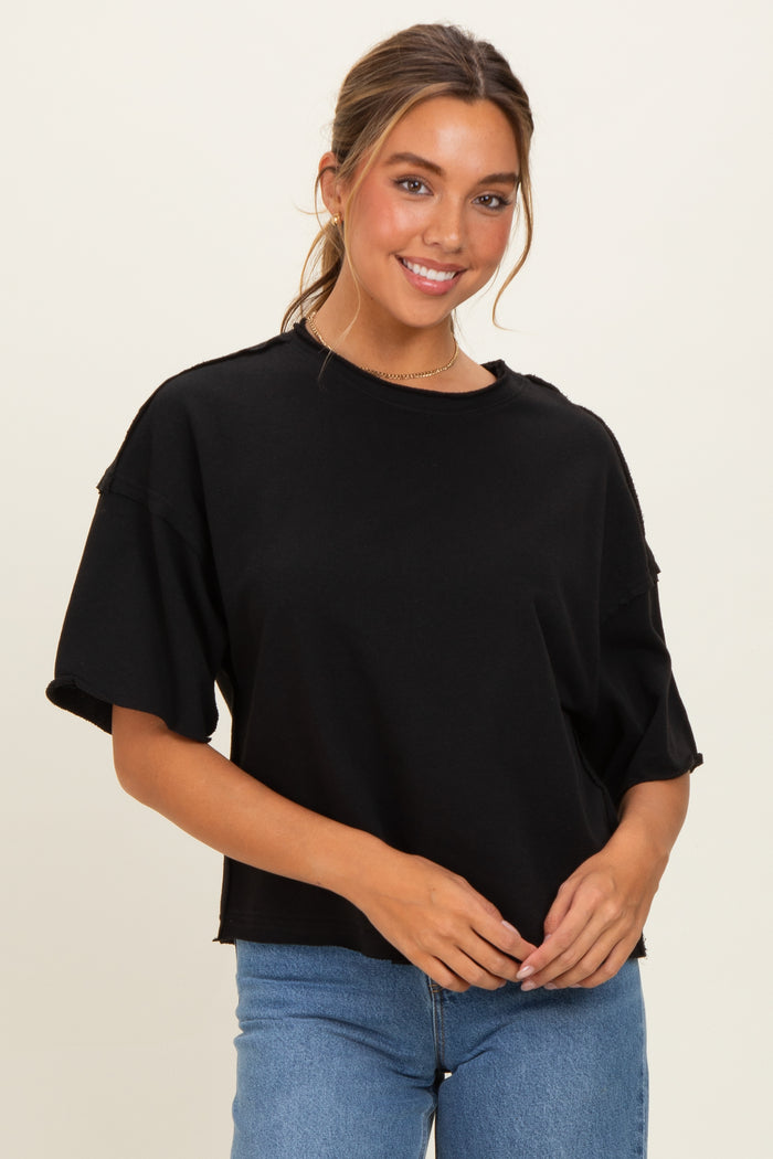 woman wearing a black oversized short sleeve top with a relaxed fit and denim jeans