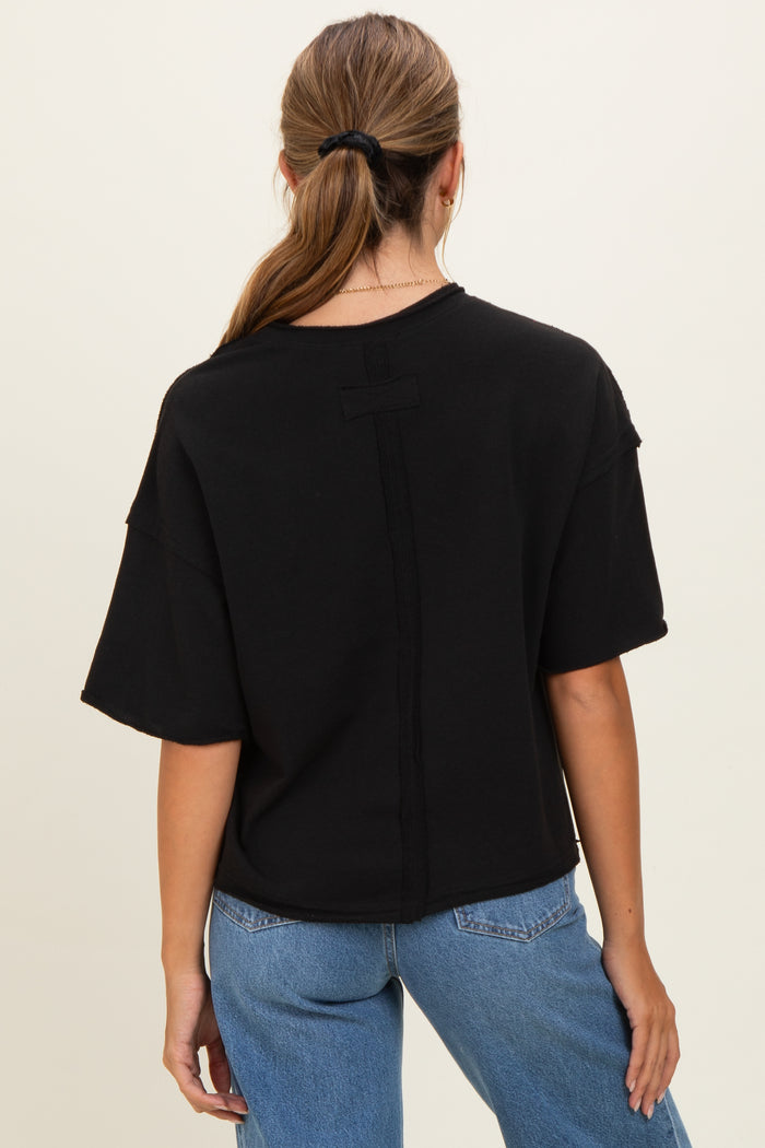 woman wearing a black oversized t-shirt with a minimalistic design and dropped shoulders, viewed from the back