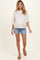 woman wearing a floral maternity sweatshirt with three-quarter sleeves and denim shorts