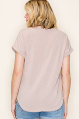 woman wearing a light pink short sleeve top with rolled sleeves and a curved hem, viewed from the back