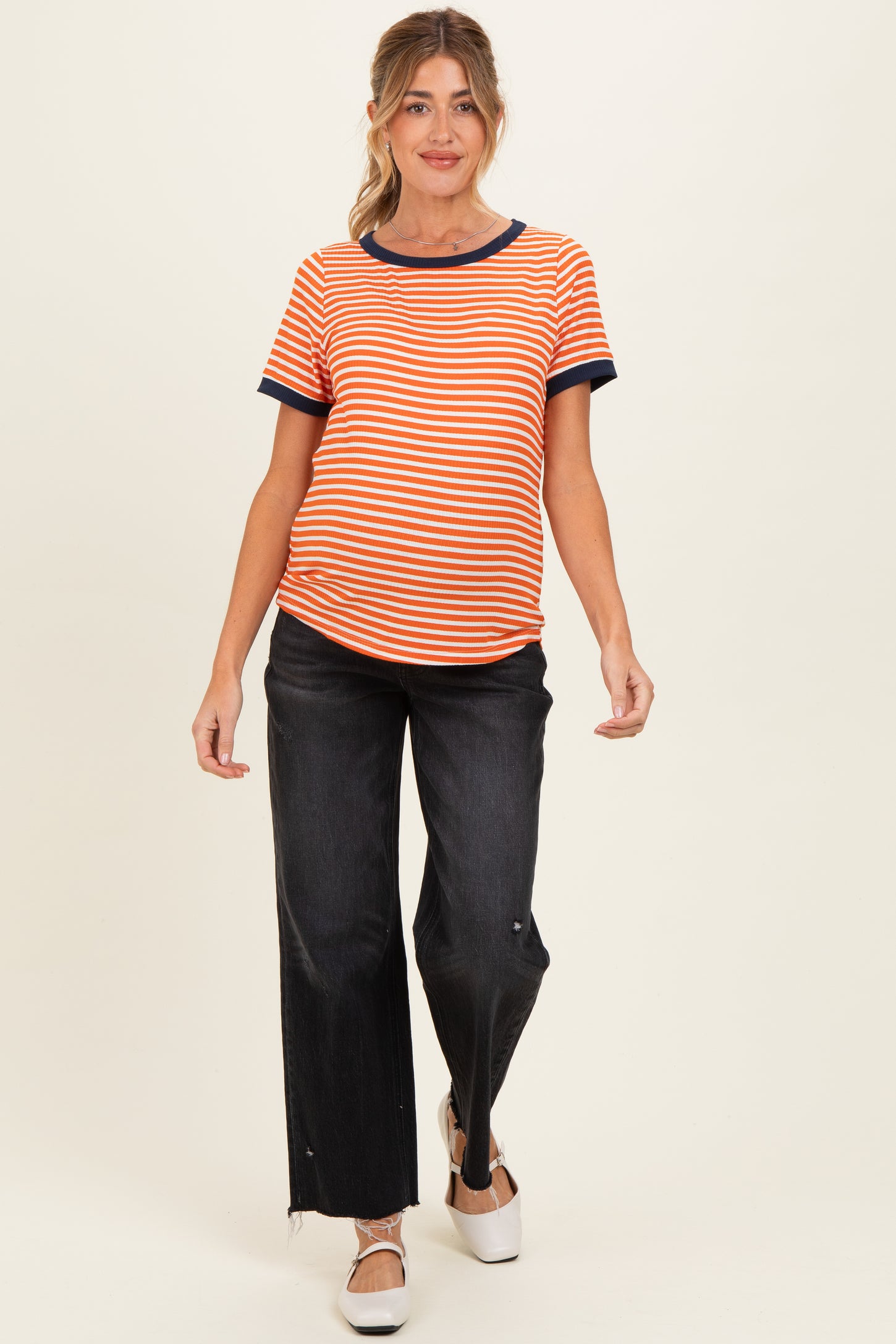 woman wearing a striped orange and blue maternity t-shirt and black wide-leg jeans, showing her baby bump