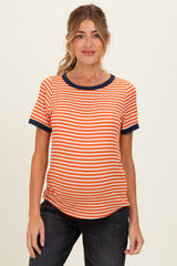 woman wearing an orange and white striped maternity top with navy blue trim and a visible baby bump