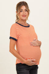 woman wearing a striped orange and navy maternity top and cradling her baby bump