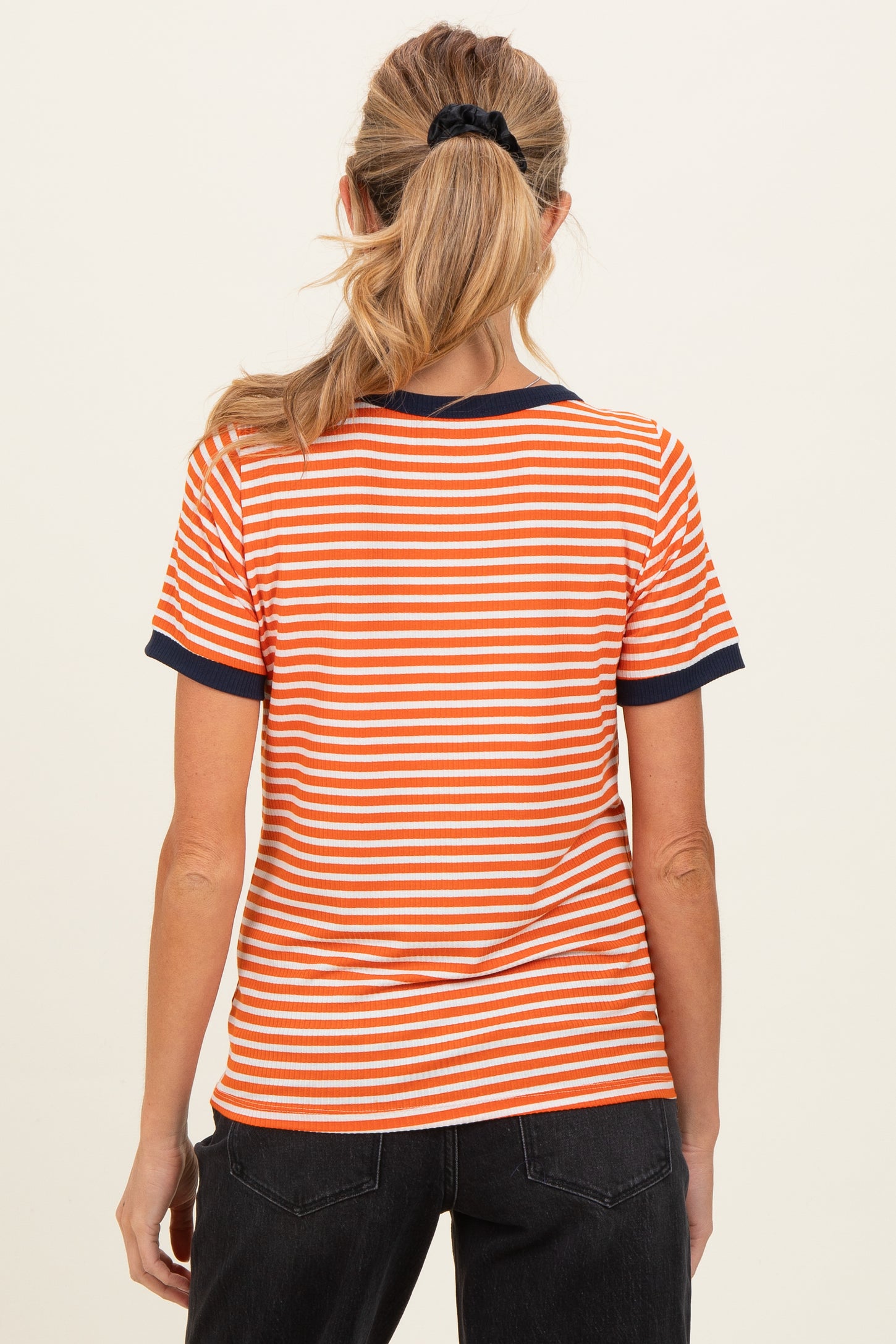 woman wearing an orange and white striped maternity top with navy trim, viewed from the back