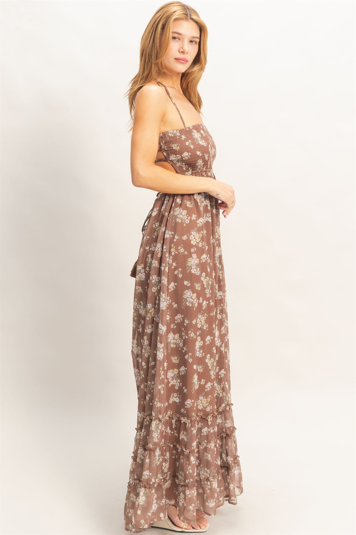 woman wearing a brown floral maxi dress with ruffled hem and spaghetti straps