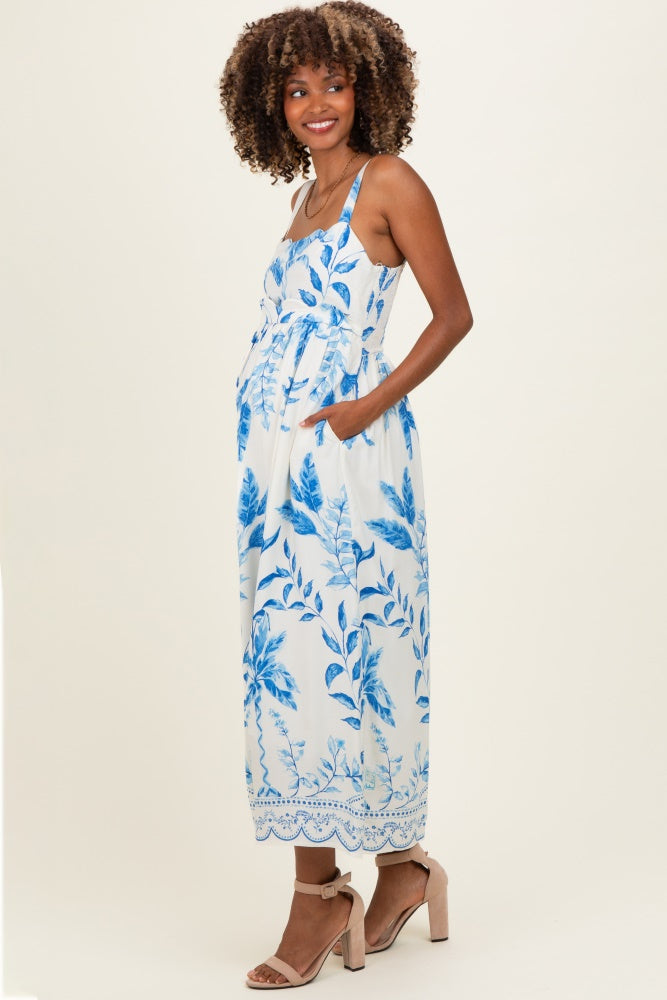 woman wearing a blue and white floral print maternity maxi dress with pockets and a visible baby bump