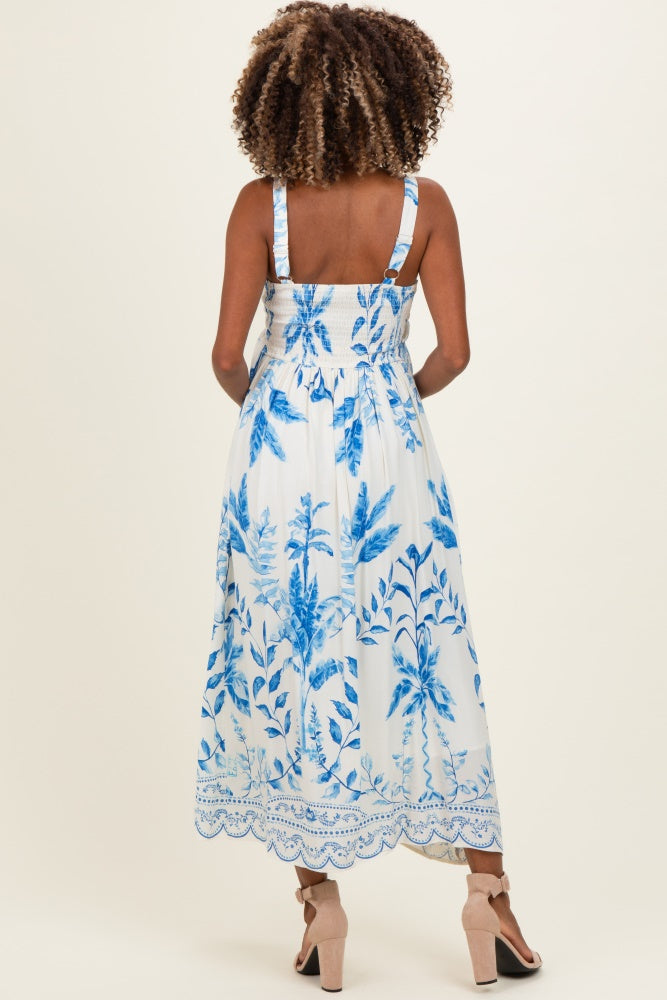 woman wearing a floral print maternity dress in white and blue, featuring a smocked back and adjustable straps