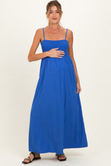woman wearing a blue maternity maxi dress with smocked bodice and holding her baby bump