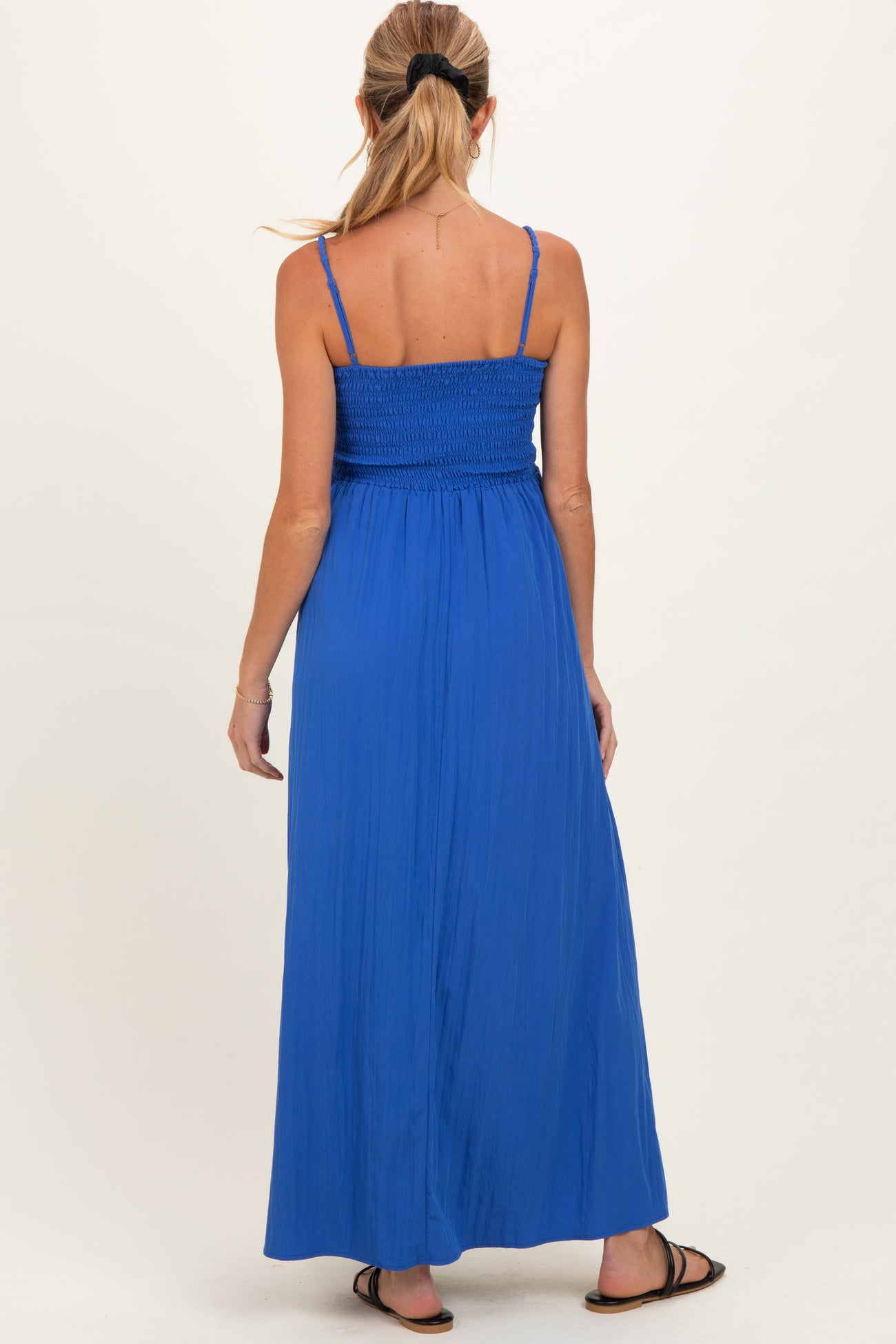 woman wearing a bright blue smocked back maternity maxi dress, showing a flowing skirt and adjustable straps