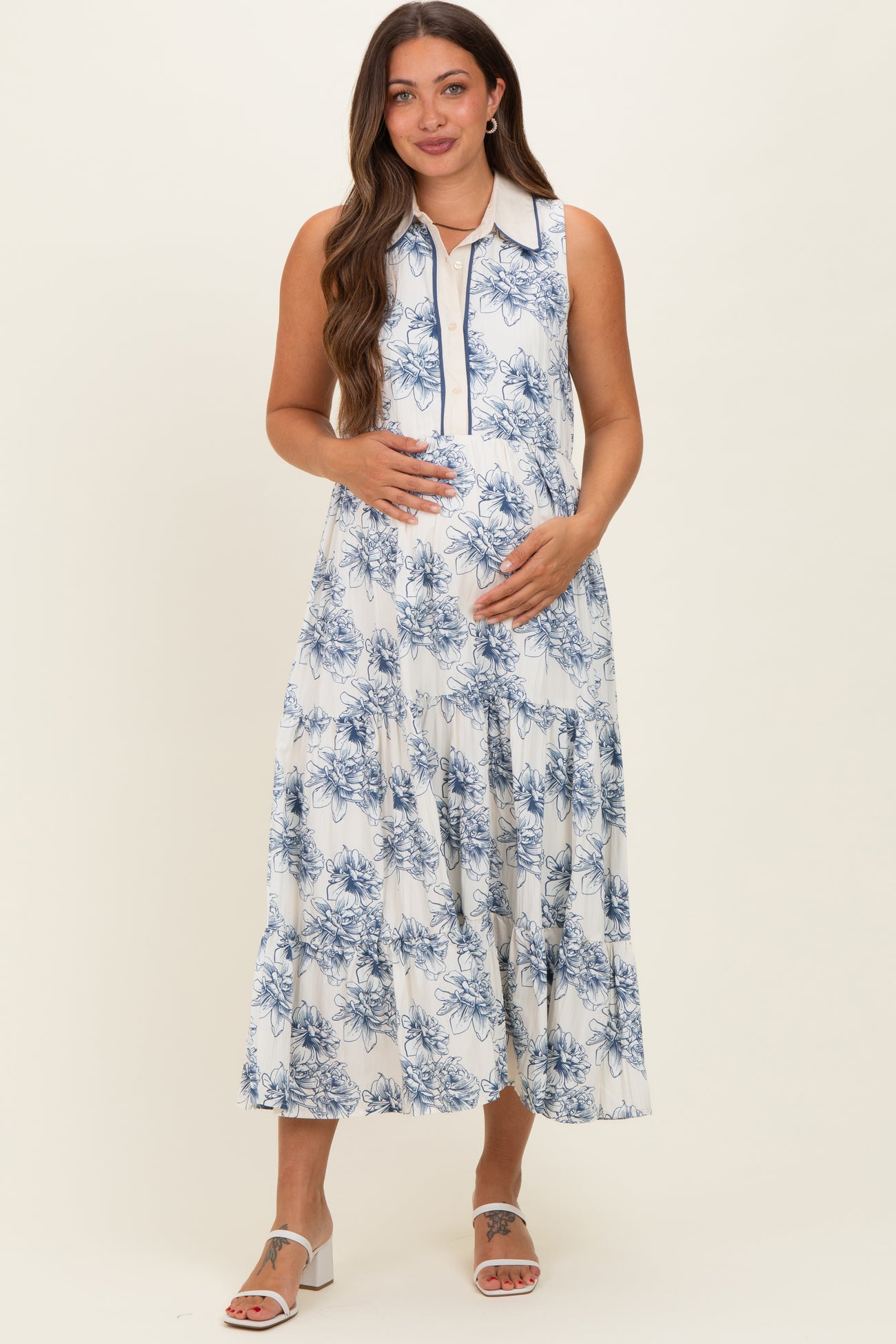 woman wearing a floral print maternity dress with a collared neckline and tiered skirt, showing her baby bump
