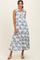 woman wearing a sleeveless white maxi dress with blue floral print and a collared neckline