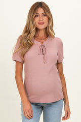 woman wearing a soft pink short sleeve maternity top with a tie detail and a visible baby bump