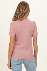 woman wearing a dusty rose short sleeve maternity top with a ribbed texture and a fitted style, seen from the back