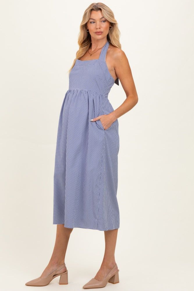 woman wearing a blue and white checked maternity dress with pockets and a gathered waist, showcasing her baby bump