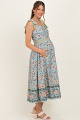 woman wearing a floral maternity dress with bow straps and a baby bump, featuring a fitted waist and pockets