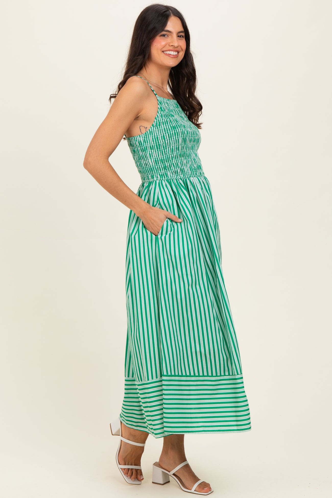 woman wearing a green and white striped maxi dress with a smocked bodice and pockets