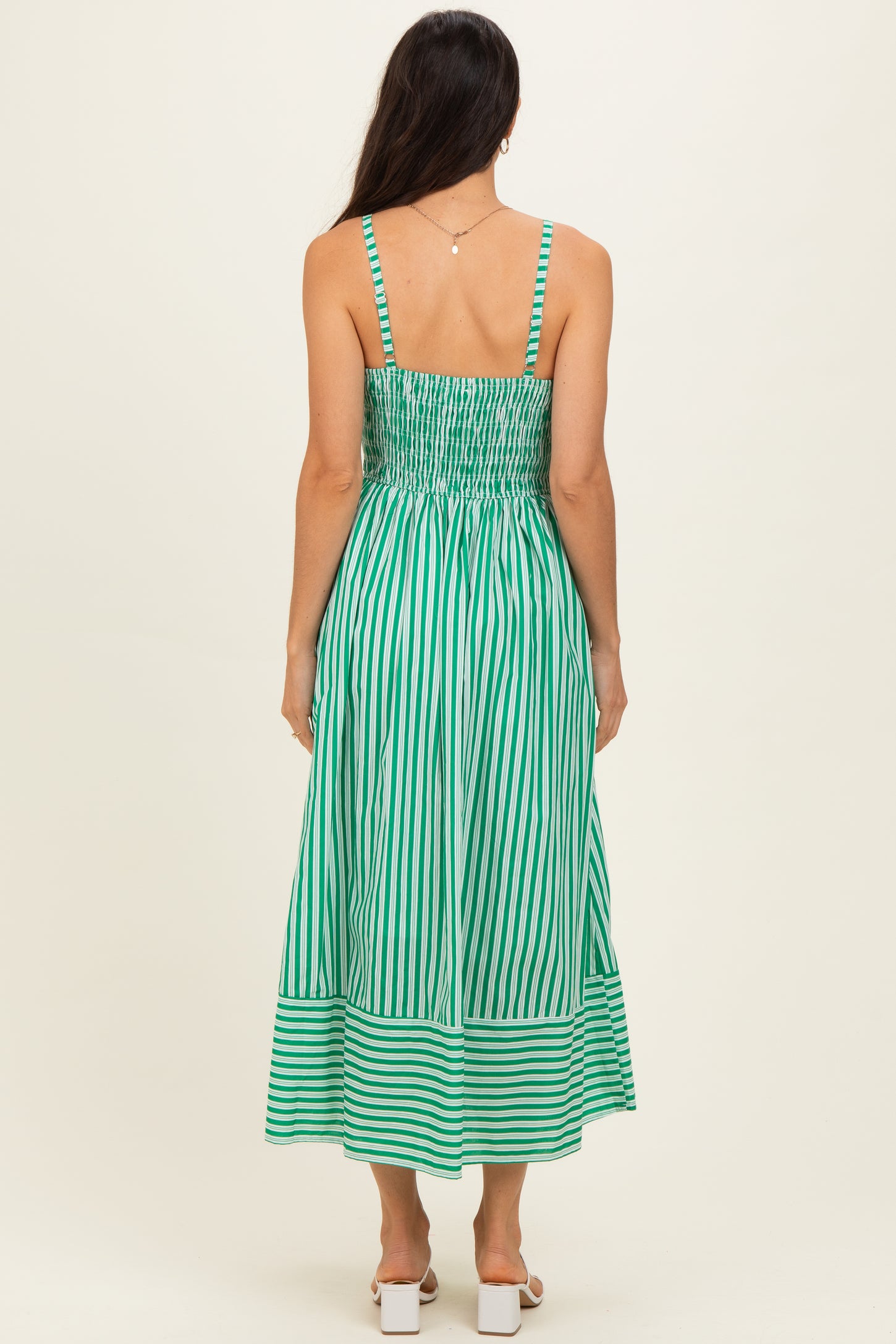 woman wearing a green and white striped backless maxi dress with smocking detail and a flowy skirt