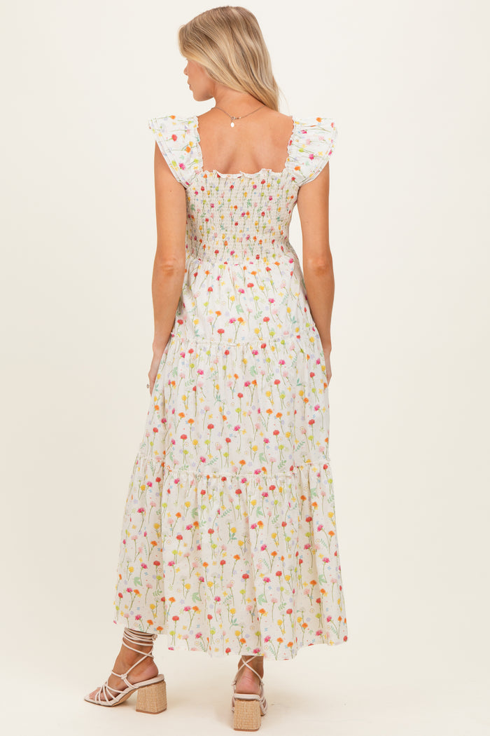 woman wearing a floral print maternity maxi dress with ruffle sleeves, showing a smocked back and tiered skirt