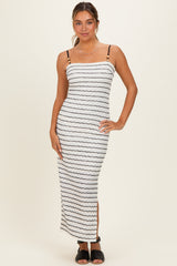 woman wearing a white striped maxi dress with spaghetti straps and side slits, standing against a neutral background