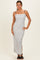 woman wearing a white striped maxi dress with spaghetti straps and side slits, standing against a neutral background