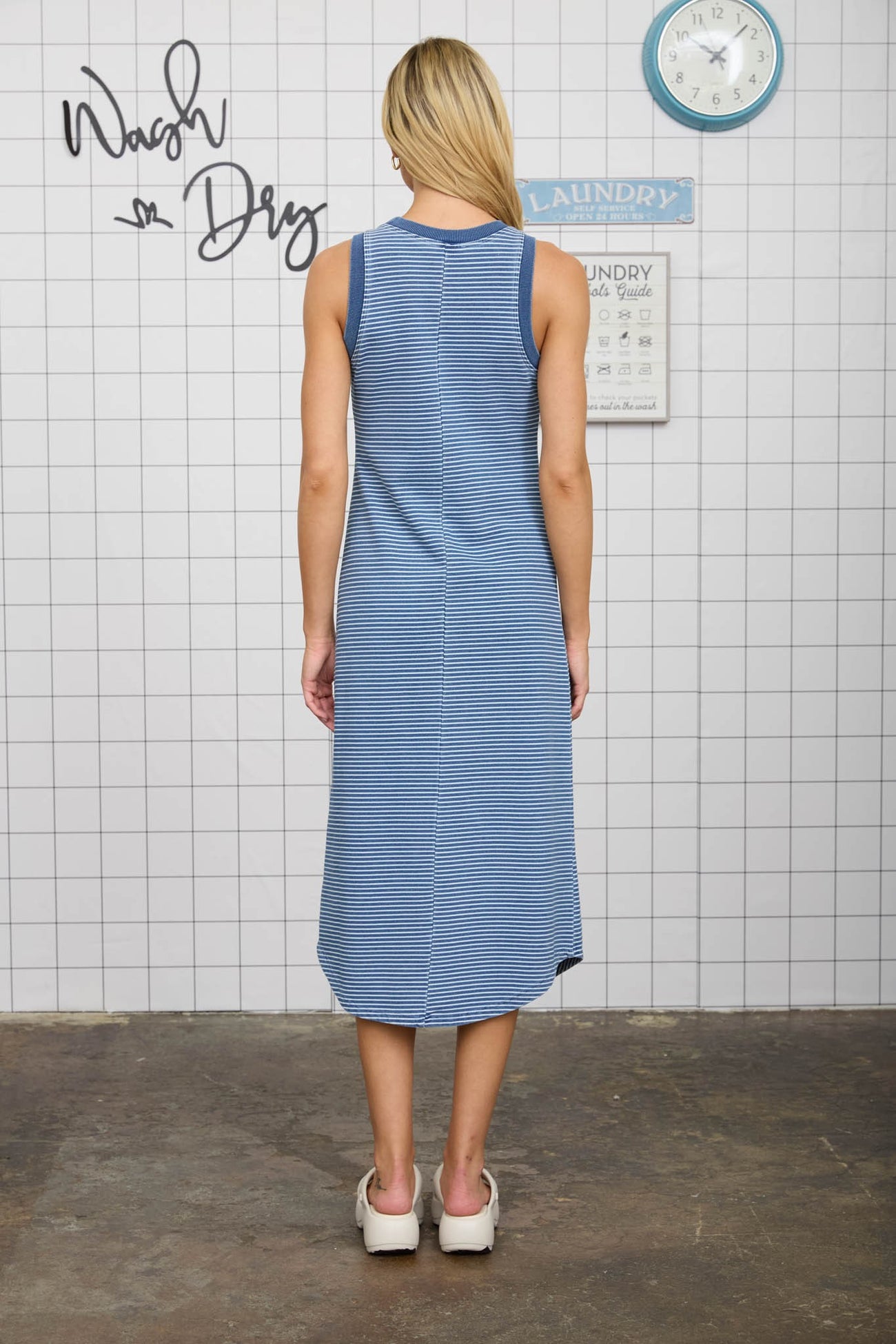 woman wearing a navy and white striped sleeveless maxi dress, showing the back view and styled for casual wear