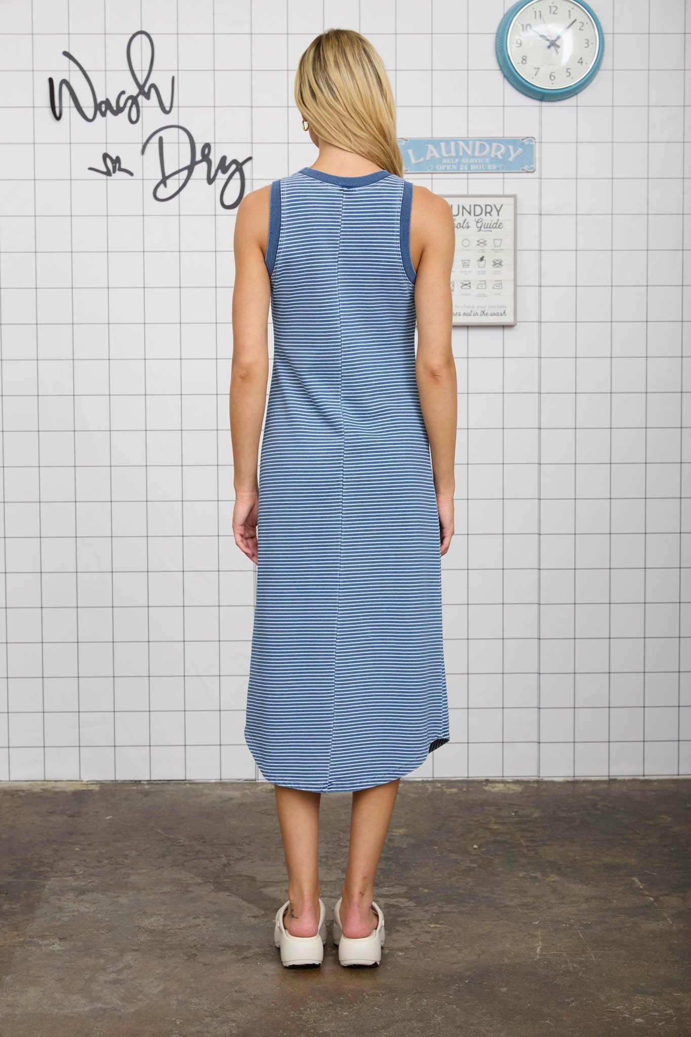 woman wearing a navy and white striped sleeveless maxi dress, showing the back view and styled for casual wear