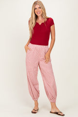 woman wearing a red short sleeve henley top and red and white striped tapered pants with pockets