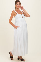 woman wearing a white maternity maxi dress with buttons and pockets, showcasing her baby bump
